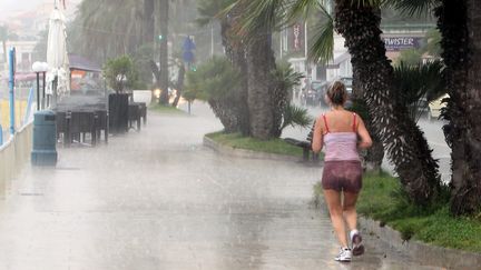 Une femme fait son jogging sous la pluie &agrave; Menton (Alpes-Maritimes), le 13 ao&ucirc;t 2014. (ERIC DULIERE / MAXPPP)