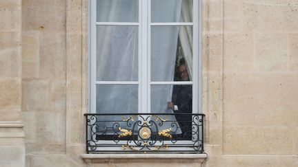 François Hollande observe l'extérieur de l'Elysée depuis une fenêtre du palais présidentiel, en attendant l'arrivée d'Emmanuel Macron. (REUTERS)