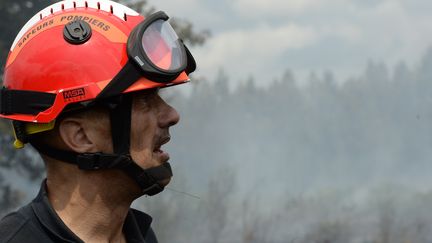 Les visages sont marqu&eacute;s par la fatigue apr&egrave;s des heures de lutte contre l'incendie. En arri&egrave;re-plan, le sol continue de d&eacute;gager de la fum&eacute;e. Mais la situation s'am&eacute;liore le lundi 27 juillet. La pr&eacute;fecture annonce que les habitants vont pouvoir rejoindre progressivement leur maison. Pr&egrave;s de 600 hectares ont br&ucirc;l&eacute; en Gironde. C'est l'incendie le plus important en France depuis quatre ans. (MEHDI FEDOUACH / AFP)