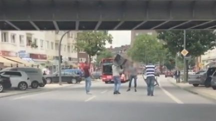 Des personnes, armées de chaises et de fauteuils, tentent d'encercler un homme suspecté d'avoir mené une attaque au couteau qui a fait un mort et six blessés, à Hambourg (Allemagne), le 28 juillet 2017. (FRANCE TELEVISIONS)