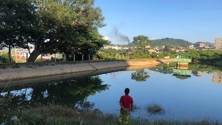 Un homme observe un panache de fumée qui s'élève depuis une base militaire à Lashio (Birmanie), où des affrontements opposent la junte et des groupes armés, le 7 novembre 2023. (AFP)