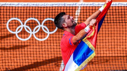 Novak Djokovic brandit le drapeau national de la Serbie après sa victoire aux Jeux olympiques de Paris, le 4 août 2024. (ALEXANDER SHCHERBAK / SIPA)