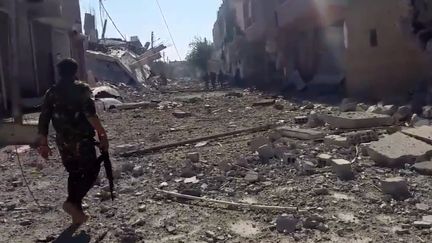 Un&nbsp;combattant des Forces démocratiques syriennes&nbsp;dans une rue dévastée de Raqqa, en Syrie, libérée de Daesh le 17 octobre 2017. (OMAR OUAHMANE / FRANCEINFO)