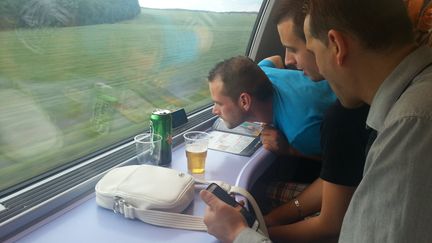 Des voyageurs d'un TGV Paris-Strasbourg tentent de suivre le match France-Nigeria sur un t&eacute;l&eacute;phone, le 30 juin 2014. (YANN THOMPSON / FRANCETV INFO)