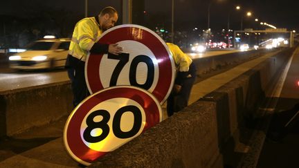 Des agents remplacent un panneau de limitation &agrave; 80 km/h par un autre &agrave; 70 km/h, sur le p&eacute;riph&eacute;rique parisien, le 7 janvier 2014. (JACQUES DEMARTHON / AFP)