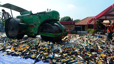 Des centaines de bouteilles de boissons alcoolisées et de DVD pornographiques piratés sont détruits dans un poste de police de Jakarta, le 8 juillet 2013.  (AFP PHOTO / ADEK BERRY)