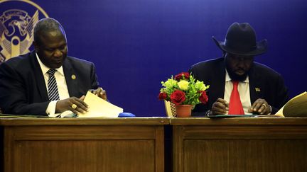 Le président du Soudan du Sud, Salva Kiir, et le chef rebelle Riek Machar, signent un accord pour le partage du pouvoir, le 5 août 2018 à Khartoum (Soudan).&nbsp; (ASHRAF SHAZLY / AFP)