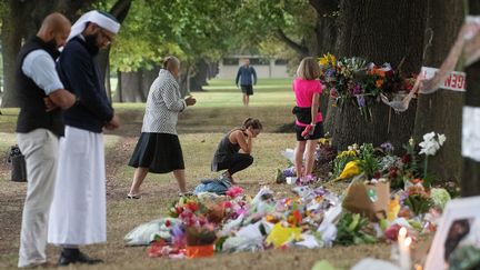 Des passants viennent se recueillir et déposer des fleurs près de la mosquée Masjid Al Noor où de nombreux fidèles ont été tués à Christchurch (Nouvelle-Zélande), le 19 mars 2019.

 (MARTY MELVILLE / AFP)