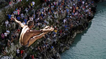 Un comp&eacute;titeur s'&eacute;lance d'un pont lors d'une concours de plongeon &agrave;&nbsp;Kanal ob Soci (Slov&eacute;nie), le 17 ao&ucirc;t 2014. (SRDJAN ZIVULOVIC / REUTERS)