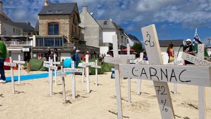 À Quiberon, le collectif Dispac'h a planté de nombreuses croix avec le nom de villes bretonnes avec leur taux de résidence secondaire, au premier plan, Carnac avec 72%.  (NICOLAS CORBARD / FRANCE TELEVISIONS)