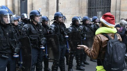 Des membres des forces de l'ordre font face à une manifestante lors d'un rassemblement de "gilets jaunes" à Paris, le 11 décembre 2018. (STEPHANE DE SAKUTIN / AFP)