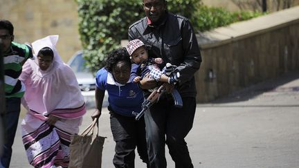 Un policier kenyan &eacute;vacue un b&eacute;b&eacute; &agrave; l'ext&eacute;rieur du centre commercial Westgate de Nairobi (Kenya) vis&eacute; par une attaque terroriste le 21 septembre 2013. (SIMON MAINA / AFP)