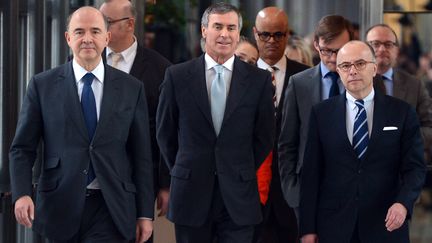 Pierre Moscovici, ministre de l'Economie et des Finances (G), aux c&ocirc;t&eacute;s de J&eacute;r&ocirc;me Cahuzac, ex-ministre du Budget, et Bernard Cazeneuve, son successeur, lors de la passation de pouvoir entre ces deux derniers, le 20 mars 2013 &agrave; Bercy. (MIGUEL MEDINA / AFP)