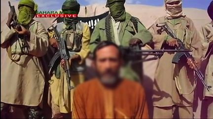 Des combattants d'Aqmi avec un otage, Daniel Larribe,&nbsp;dans une vid&eacute;o diffus&eacute;e le 10 ao&ucirc;t 2012. (SAHARA MEDIA / AFP)