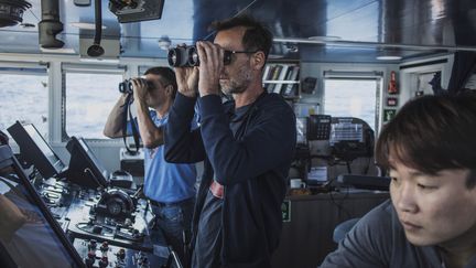 En direction du mont sous-marin Vema (Afrique du Sud), l'océanographe de Greenpeace Thilo Maack (à gauche) et le capitaine de l'"Arctic Sunrise" Mike Flnchen regardent le large à&nbsp;la jumelle, le 30 octobre 2019. (MARCO LONGARI / AFP)