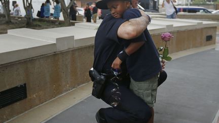 Un policier blanc prend dans ses bras un enfant noir près d'un monument dédié aux policiers dans la ville de Dallas, le 10 juillet 2016. Une rose à la main, le petit garçon est venu saluer la mémoire des cinq policiers tués dans cette grande ville du Texas. Un instant de tendresse qui tranche avec la brutalité policière que dénoncent de nombreux américains. «Les attaques contre la police desservent la cause de ceux qui s'inquiètent légitimement des carences du système judiciaire» a précisé Barack Obama, premier président noir des Etats-Unis. (Reuters/ Carlo Allegri)