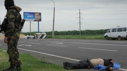 &nbsp; (Tout près de l'entrée de Donetsk, le corps d'un combattant tué dans un combat. Derrière, une affiche électorale pour le candidat Valéry Konovaliuk, dont on lit le slogan :  "Nous avons besoin de la paix" © Radio France / Jean-Marie Porcher)