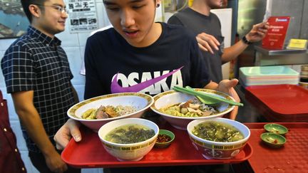 Un client du&nbsp;Hong Kong Soya Sauce Chicken Rice &amp; Noodles, restaurant classé une étoile au guide Michelin, repart avec son plateau. (ROSLAN RAHMAN / AFP)