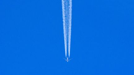 Un avion laisse derrière lui des traînées de condensation, appelées parfois "chemtrails", un mot à connotation complotiste. (YURI KADOBNOV / AFP)