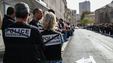 Des policiers, avec le dossard "police judiciaire" barré, rassemblés en haie d'honneur pour saluer le directeur de la PJ de Marseille Eric Arella, démis de ses fonctions, le 7 octobre 2022. (NICOLAS TUCAT / AFP)