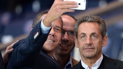 L'ancien pr&eacute;sident fran&ccedil;ais Nicolas Sarkozy pose pour un selfie avec des admirateurs dans les tribunes du Parc des Princes &agrave; Paris, le 31 ao&ucirc;t 2014. (JEFFROY GUY / SIPA)