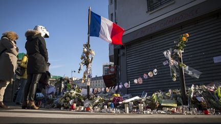 Des personnes déposent des fleurs devant le restaurant Le petit Cambodge, à Paris, le 23 novembre 2015. (LIONEL BONAVENTURE / AFP)