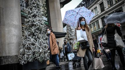 Des passants masqués dans la rue&nbsp;à Paris, le 24 décembre 2020. (STEPHANE DE SAKUTIN / AFP)