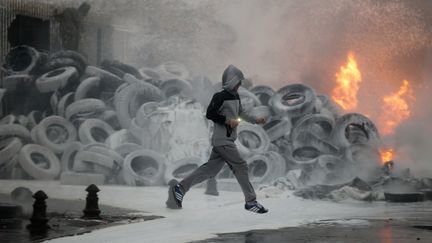 Un homme court devant un tas de pneus enflamm&eacute;s par des agriculteurs en col&egrave;re devant la pr&eacute;fecture de la Manche, &agrave; Saint-L&ocirc;, mercredi 19 ao&ucirc;t 2015. (CHARLY TRIBALLEAU / AFP)