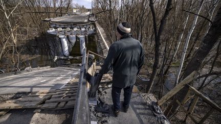 Un homme se tient devant un pont détruit près du village de Bohorodychne, dans la région du Donbass (Ukraine), le 5 avril 2022.&nbsp; (FADEL SENNA / AFP)