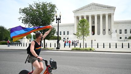 Un cycliste agite un drapeau arc-en-ciel devant la Cour suprême, le 15 juin 2020, à Washington DC (Etats-Unis). (JIM WATSON / AFP)