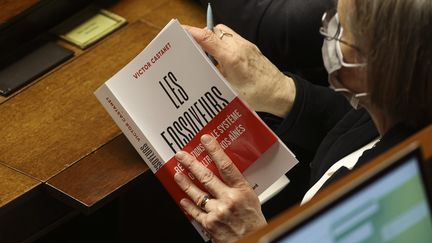 Une députée tient le livre "Les Fossoyeurs" de Victor Castanet entre les mains&nbsp;lors des questions au gouvernement&nbsp;sur des maltraitances&nbsp;qu'il dénonce sur les résidents des Ehpad du groupe Orpea, le 25 janvier 2022. (S?BASTIEN MUYLAERT / MAXPPP)