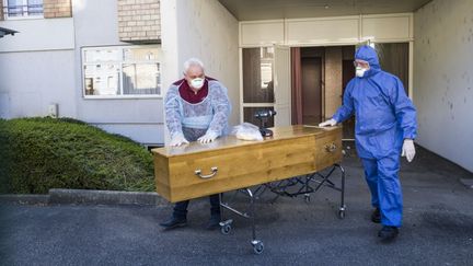 Des employés funéraires transportent le cercueil d'une victime du Covid-19 dans un Ehpad à Mulhouse (Haut-Rhin), le 5 avril 2020. (SEBASTIEN BOZON / AFP)