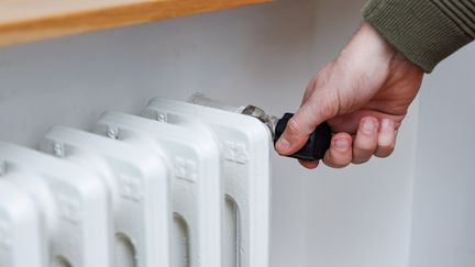 Personne réduisant le thermostat de son radiateur. (ZORANM / E+ / GETTY IMAGES)