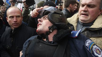 Des manifestants attrapent un policier par son casque en tentant de p&eacute;n&eacute;trer dans un b&acirc;timent officiel de Kiev (Ukraine), le 2 octobre 2013. (YURY KIRNICHNY / AFP)