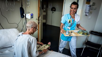 Un patient se fait servir un repas à l'hôpital, le 10 septembre 2018, à l'hôpital&nbsp;Léon-Berard, à Lyon. (JEAN-PHILIPPE KSIAZEK / AFP)