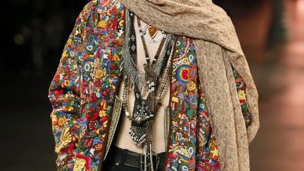 Les défilés se sont achevés avec Saint Laurent, dont le designer Hedi Slimane a présenté une collection hippie. Revoici les années 70 ! Vestes en daim, ponchos, chemises à fleur, djellaba revisitée, bijoux ethniques, lunettes rondes: Hedi Slimane ne laisse pas planer le doute sur son inspiration. Il en joue aussi, comme avec une veste militaire à franges. Les chapeaux donnent eux un côté folk à la collection, qui se la joue rebelle. Car le défilé est bien signé Hedi Slimane, créateur qui a lancé la mode androgyne dans les années 2000, avec des silhouettes ultra-slim. Les mannequins portent des jeans noirs dans lesquels seuls les hommes ultra-filiformes pourront entrer. Les précédentes collections d'Hedi Slimane pour Saint Laurent étaient très rock et cette influence est toujours présente, avec perfectos et vestes brillantes. Le créateur a invité les copines de l'homme Saint Laurent à défiler. Elles aussi sont des hippies avec leurs robes longues. Le défilé est d'ailleurs dédié à Betty (Catroux) et Loulou (De la Falaise), qui furent deux muses d'Yves Saint-Laurent. "Ca me rappelle des souvenirs avec Yves. A Marrakech, oui", confie-t-elle à des journalistes. Elle "adore" Hedi Slimane, qui est "sans aucun doute le Saint Laurent d'aujourd'hui". Pour Pierre Bergé, la collection est "formidable, comme tout ce que fait Hedi". "Il aborde la mode avec un regard moderne et nouveau", estime-t-il. Est-il tenu à respecter les codes? "Yves Saint-Laurent est mort et il fait ce qu'il veut et comme il veut", répond Pierre Bergé.
 (PATRICK KOVARIK / AFP)