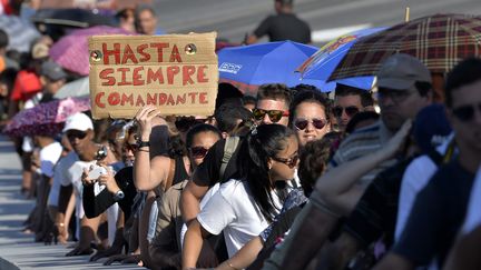 Dans cette file d'attente, lundi 28 novembre 2016, une femme tient un panneau sur lequel est écrit "Hasta siempre comandante" (Pour toujours, Commandant).&nbsp;Une référence à la chanson écrite au moment où Ernesto Che Guevara a&nbsp;quitté le gouvernement de Fidel Castro. (PEDRO PARDO / AFP)