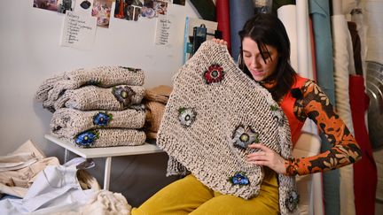 Emma Gage, la créatrice de la marque Melke, montre un de ses pulls dans son studio lors de la New York Fashion Week, le 4 février 2022 (ANGELA WEISS / AFP)