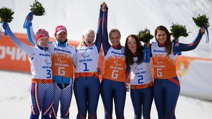 Le podium du super-G malvoyantes avec les skieuses et leurs guides, lundi à Sotchi.  (KONSTANTIN CHALABOV / RIA NOVOSTI)