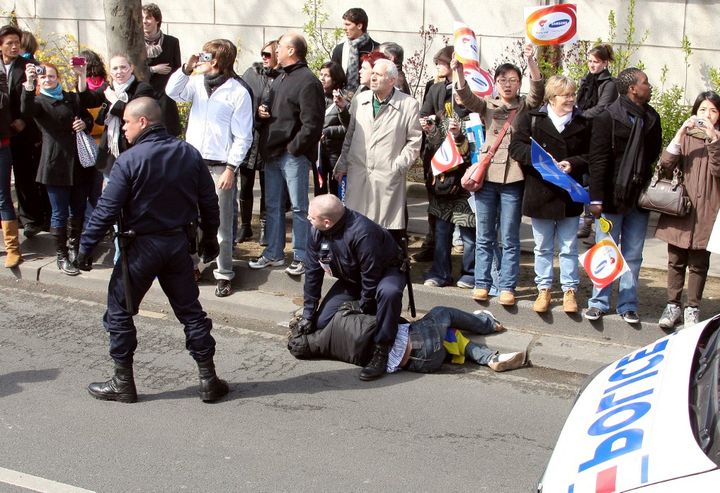 Un manifestant pro-Tibet est retenu par un policier le 7 avril 2008, lors du passage de la flamme olympique à Paris.  (PATRICK KOVARIK/AFP)