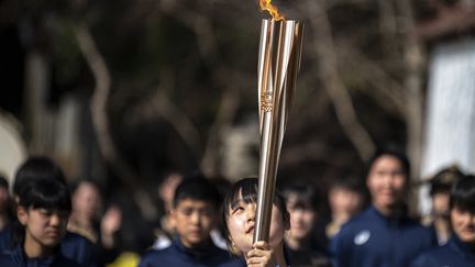 Une étudiante porte la flamme olympique, à Soma (Japon), le 26 mars 2021. (CHARLY TRIBALLEAU / AFP)