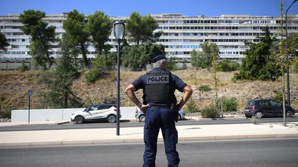 Un policier se tient devant un bâtiment du quartier Pissevin, à Nîmes, là où a eu lieu la fusillade qui a fait un mort, dans la nuit du 21 au 22 août 2023. (NICOLAS TUCAT / AFP)