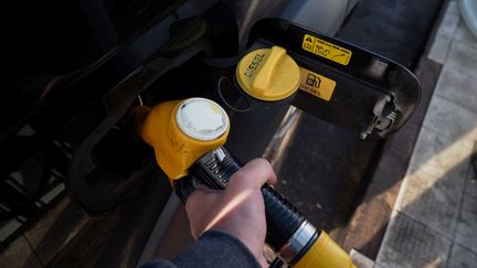 Un automobiliste, en train de mettre du gazole dans sa voiture. (GUILLAUME SOUVANT / AFP)