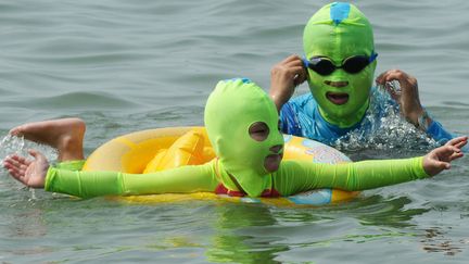 Des&nbsp;baigneuses portent un "facekini", un maillot de bain couvrant le corps et la t&ecirc;te int&eacute;gralement, sur une plage de Qingdao (Chine), le 19 ao&ucirc;t 2014. Le "facekini" est utilis&eacute; pour se prot&eacute;ger des rayons du soleil et des m&eacute;duses. (WANG HAIBIN / SIPA)