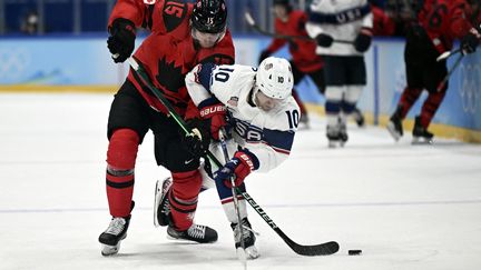 Le Canadien Adam Tambellini (à gauche) face à l'Américain Matty Beniers, lors du match de poules opposant le Canada aux Etats-Unis aux Jeux olympiques de Pékin, le 12 février 2022. (KIRILL KUDRYAVTSEV / AFP)