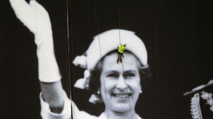 Un ouvrier installe une photo g&eacute;ante de la reine Elizabeth II &agrave; l'occasion de son jubil&eacute; de diamant &agrave; Londres (Royaume-Uni), le 25 mai 2012. (MATT DUNHAM / AP / SIPA)