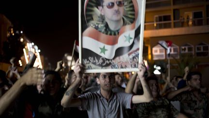 Un soldat syrien brandit un portrait de Bachar Al-Assad apr&egrave;s sa r&eacute;&eacute;lection, &agrave; Damas (Syrie), le 4 juin 2014. (DUSAN VRANIC / AP / SIPA)