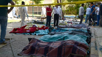 Les enqu&ecirc;teurs turcs travaillent pr&egrave;s des corps des victimes, recouverts de couverture, apr&egrave;s l'explosion qui a eu lieu dans le jardin d'un centre culturel de Suru&ccedil; (Turquie), le 20 juillet 2015.&nbsp; (ILYAS AKENGIN / AFP)