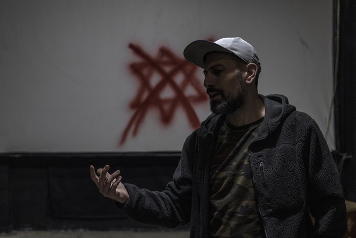 Ahmad Tubasi, directeur artistique du "Freedom Theatre", parle devant un X rouge peint à la bombe sur une étoile de David laissée par des soldats israéliens lors d'un récent raid, le 23 décembre 2023. (MARCO LONGARI / AFP)