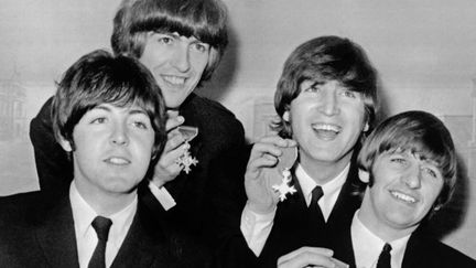 Paul McCartney, George Harrison, John Lennon et Ringo Starr avec leurs Médailles de l'Empire britannique en 1965, au Buckingham Palace.
 (PETER SKINGLEY / UPI / AFP)